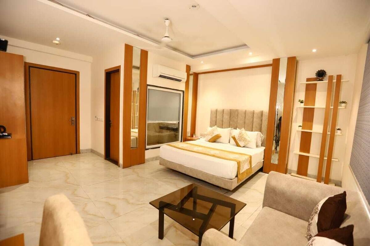 A hotel room with a large bed, a sofa, a coffee table, and a wardrobe.