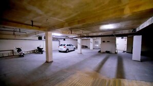 A multi-level parking garage with concrete pillars, a white car, and a motorcycle. - Hotel Anchorage Delhi IGI Airport (New Delhi)