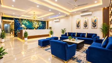 A hotel lobby with a reception desk, blue sofas, a coffee table, and a chandelier.
