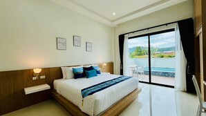 A modern hotel room with a large bed, a view of the outdoors, and a balcony with a table and chairs. - Unchan Livliness Pool Villa  (Tambon Ao Nang)