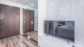 A modern bedroom with a large flat-screen TV, a wooden door, and a glass partition. - Coco Apartment Dcapital Luxury (Hanoi)
