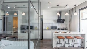 A modern kitchen with white cabinets, a marble island, and pendant lighting. - Coco Apartment Dcapital Luxury (Hanoi)