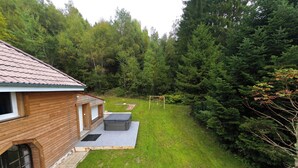 Una cabaña de madera con un porche y un columpio en un área boscosa.