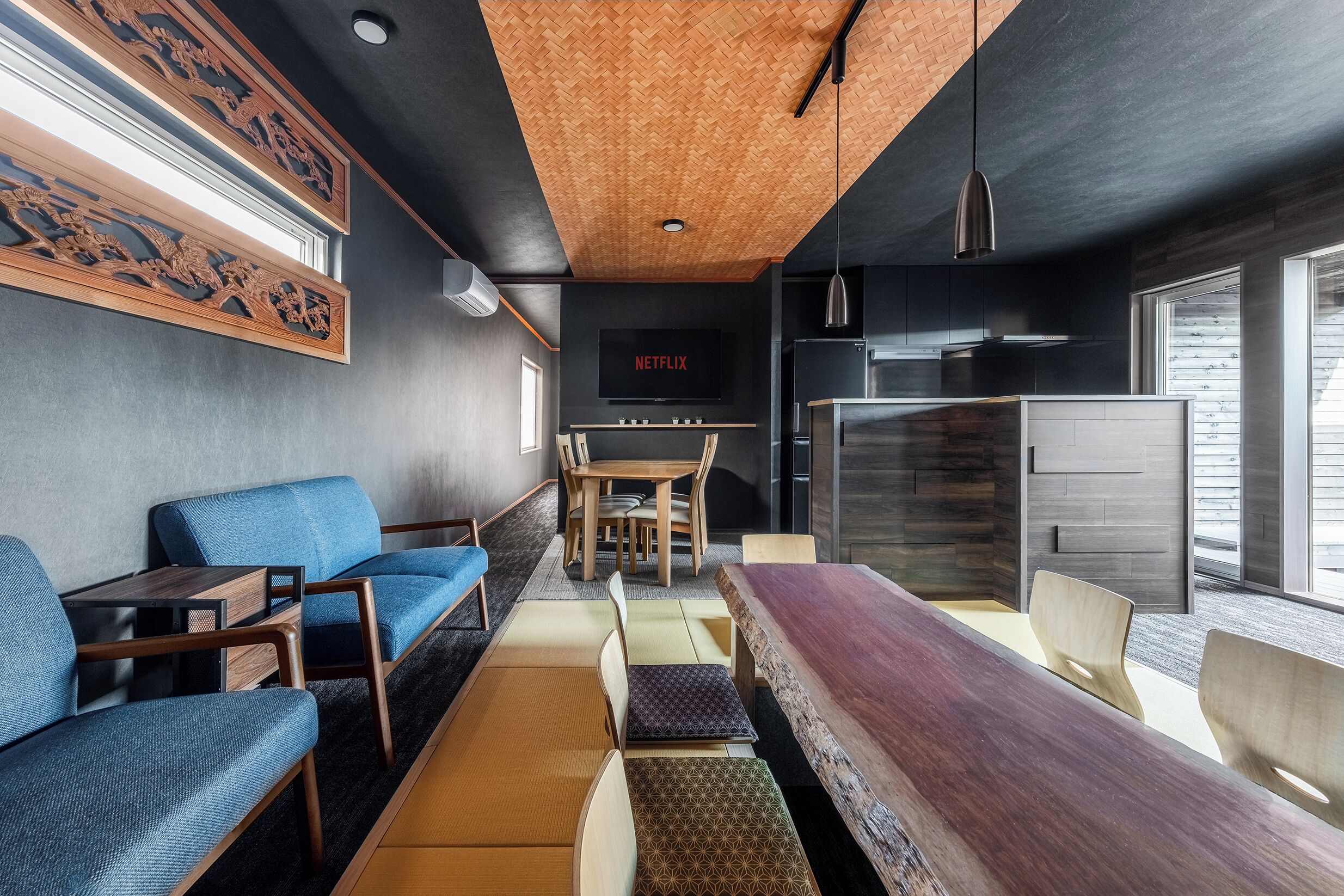 Un interior moderno con un sofá, una mesa de comedor, sillas y una pantalla de televisión mostrando 