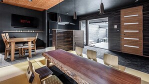 A modern kitchen with a large wooden table, built-in appliances, and a TV displaying 'NETFLIX'. - THE VILLA SEIFUMEIGETSU (Shiraoi)