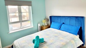 Een slaapkamer met een bed, een raam en een nachtkastje.