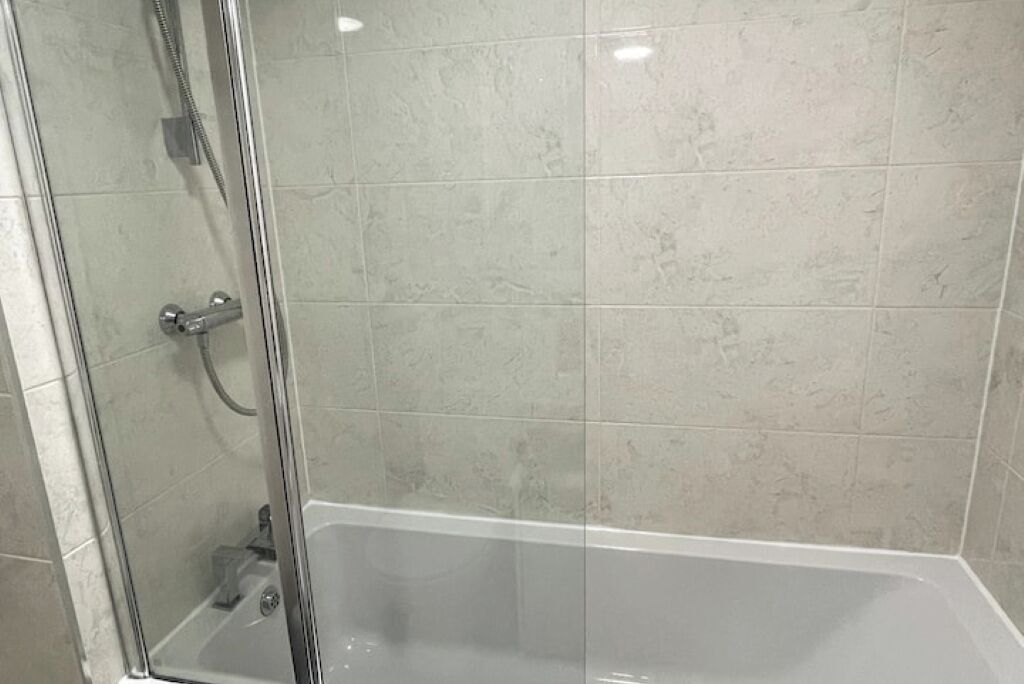 A glass-enclosed shower area with a bathtub.