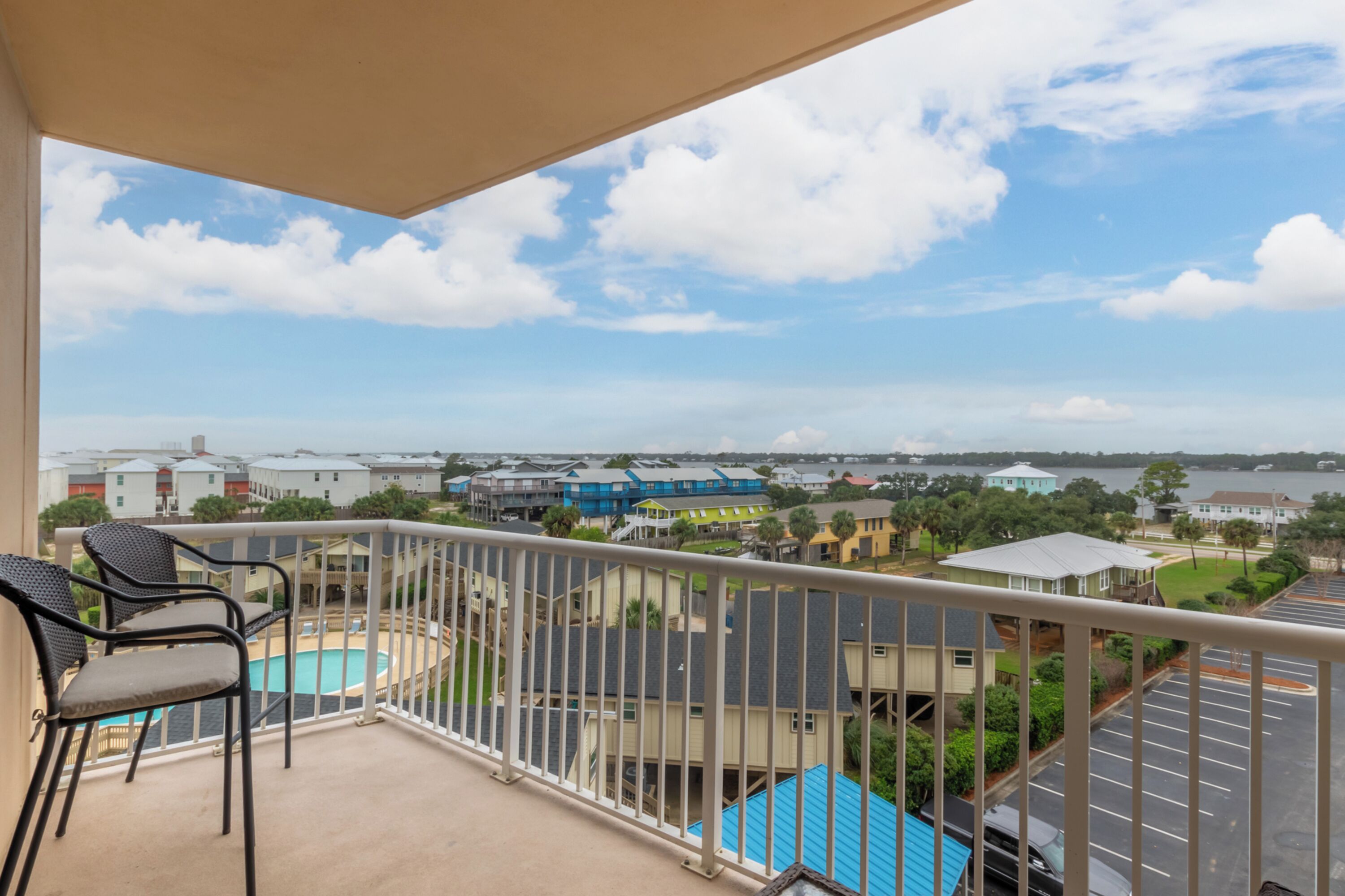 A balcony with a view of a swimming pool and surrounding buildings.