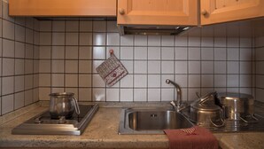 Une cuisine équipée d’un évier en acier inoxydable, d’une cuisinière et de meubles de rangement en bois.