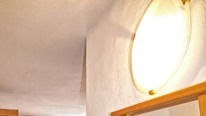 Une pièce avec un lit, un tableau, un plancher en bois et un téléviseur accroché au mur.