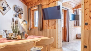 Een houten interieur met een eethoek, inclusief een tafel, stoelen, een wandgemonteerde televisie en een knus haardvuur.