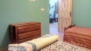 Quarto com penteadeira de madeira, colcha estampada e porta com detalhes decorativos.
