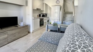 Una sala moderna con un televisor de pantalla plana, un sofá y un comedor con una mesa y sillas.