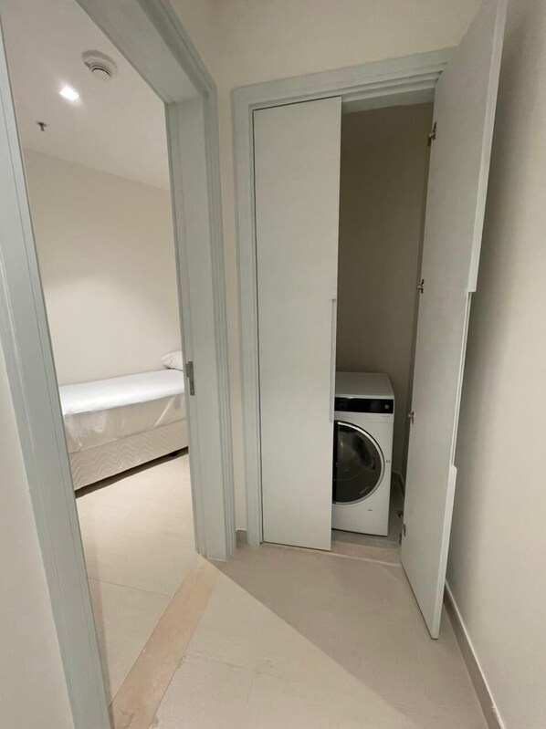 Un pasillo estrecho con una lavadora en una habitación pequeña.