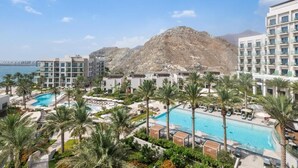 A resort with multiple swimming pools, palm trees, and a mountain in the background. - Address Residence Fujairah by Bespoke (Sharm)