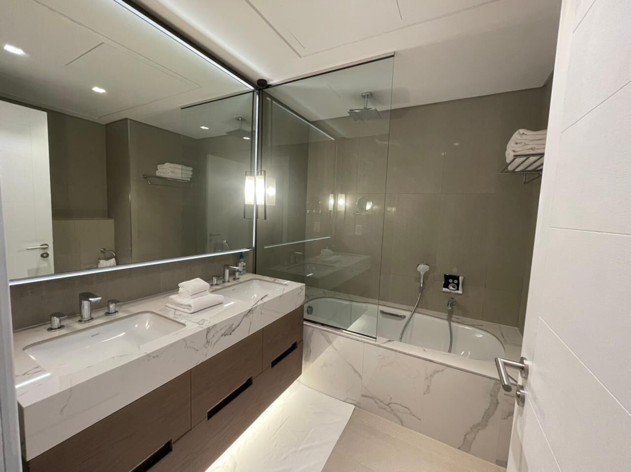 A modern bathroom with a glass-enclosed shower, a large mirror, and a dual sink vanity.