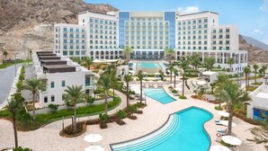A hotel with a pool, palm trees, and a mountainous backdrop. - Address Residence Fujairah by Bespoke (Sharm)