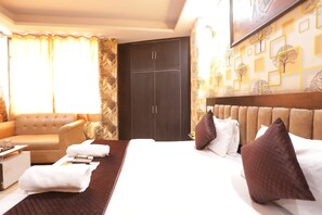 A hotel room with a bed, a sofa, a desk, and a wardrobe. - HOTEL DV PLAZA INN Near Delhi Airport (New Delhi)