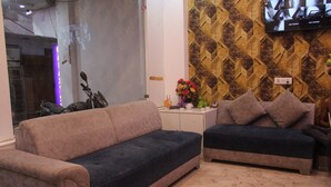 Un salon avec deux canapés, une petite table d’appoint sur laquelle est posé un vase de fleurs, et un téléviseur fixé à un mur orné d’un motif.