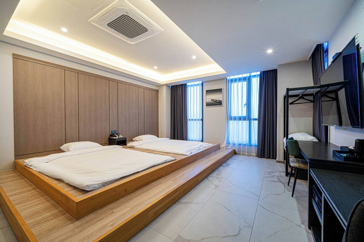 A modern hotel room with a wooden bed, a desk, and a chair.