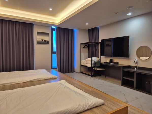 A hotel room with two beds, a desk, a chair, a TV, and a mirror. - The Western Busan Hotel by StayNEO (Busan)