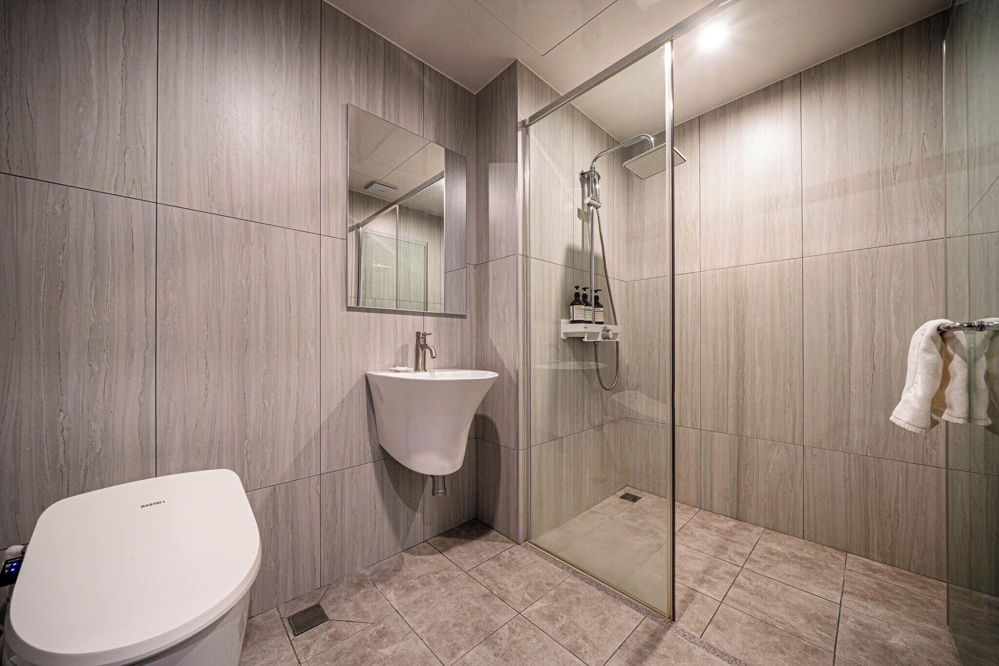 A modern bathroom with a toilet, sink, and glass-enclosed shower.