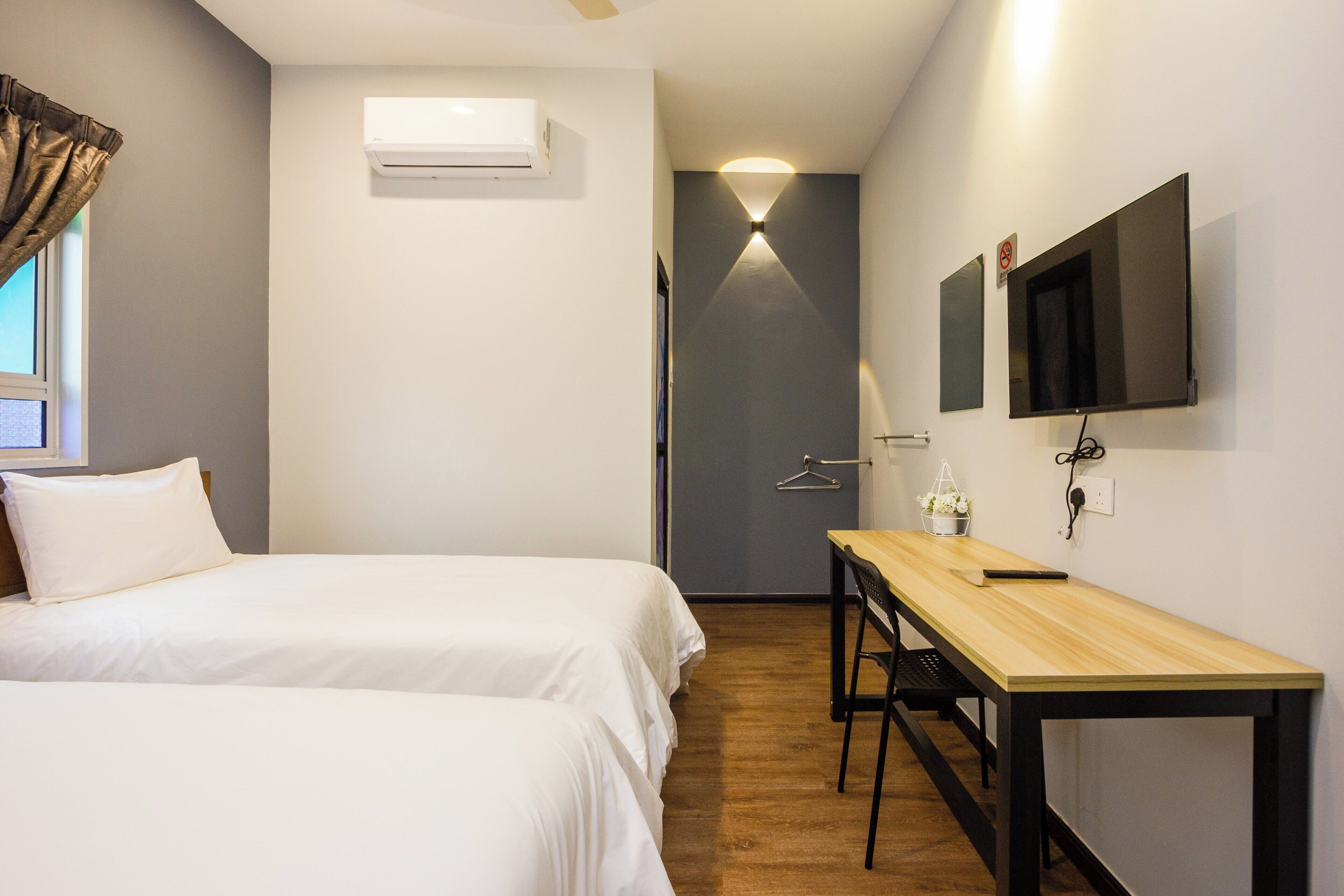 Habitación de hotel con dos camas, un escritorio, un televisor y un equipo de aire acondicionado.