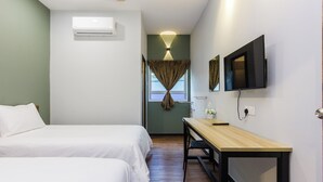 Een hotelkamer met twee bedden, een bureau, een televisie en een airconditioner.