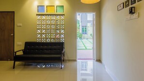 Een moderne lobby met een zwarte leren bank, een decoratieve scheiding en een plafondlamp.