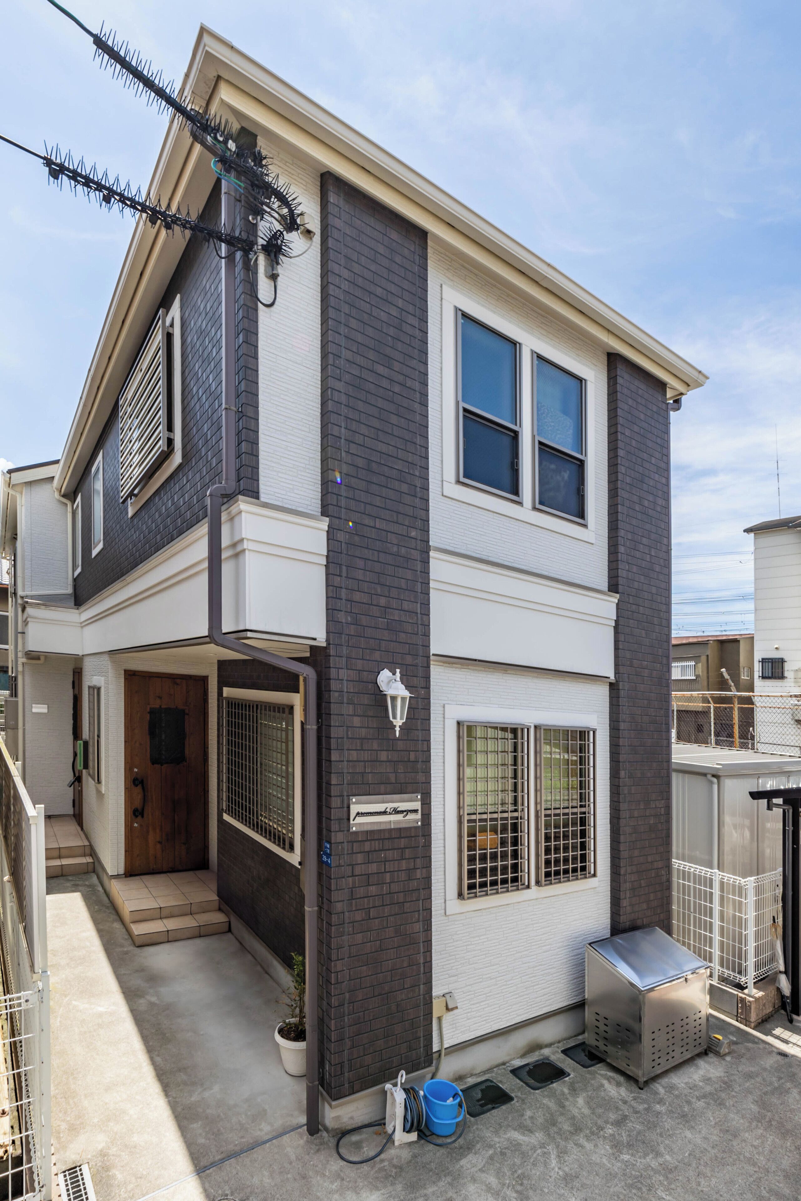 Ein zweistöckiges Wohnhaus mit Balkon, Garage und kleiner Außen-Sitzgelegenheit.