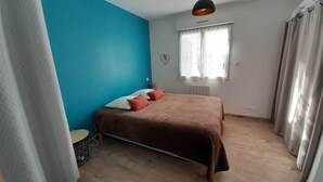 Une chambre à coucher avec un lit, une fenêtre avec des rideaux, un radiateur et un mur bleu.
