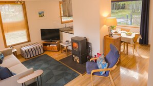 Ein gemütliches Wohnzimmer mit Fernseher, Kamin und Essbereich.