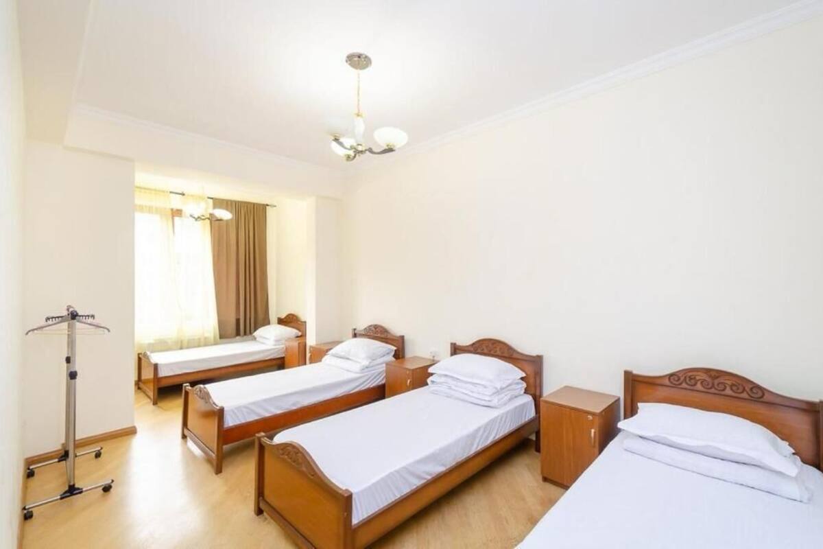 Ein Hotelzimmer mit zwei Einzelbetten, einem Holzschrank, einem Nachttisch, einer Lampe und einem Fenster mit Vorhängen.