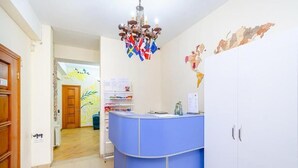 A reception area with a blue counter, white cabinets, a chandelier, and a map on the wall. - Areva Hostel (Yerevan)