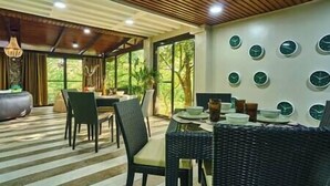 A dining area with a wooden ceiling, large windows, and a wall with multiple clocks.