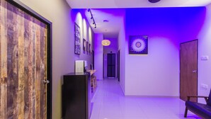 A hallway with a wooden door, a black cabinet, and a bench. - Great 5BR Garden Inn by uBook (Butterworth)