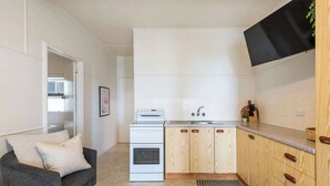 A compact kitchen with a stove, sink, and wooden cabinets.