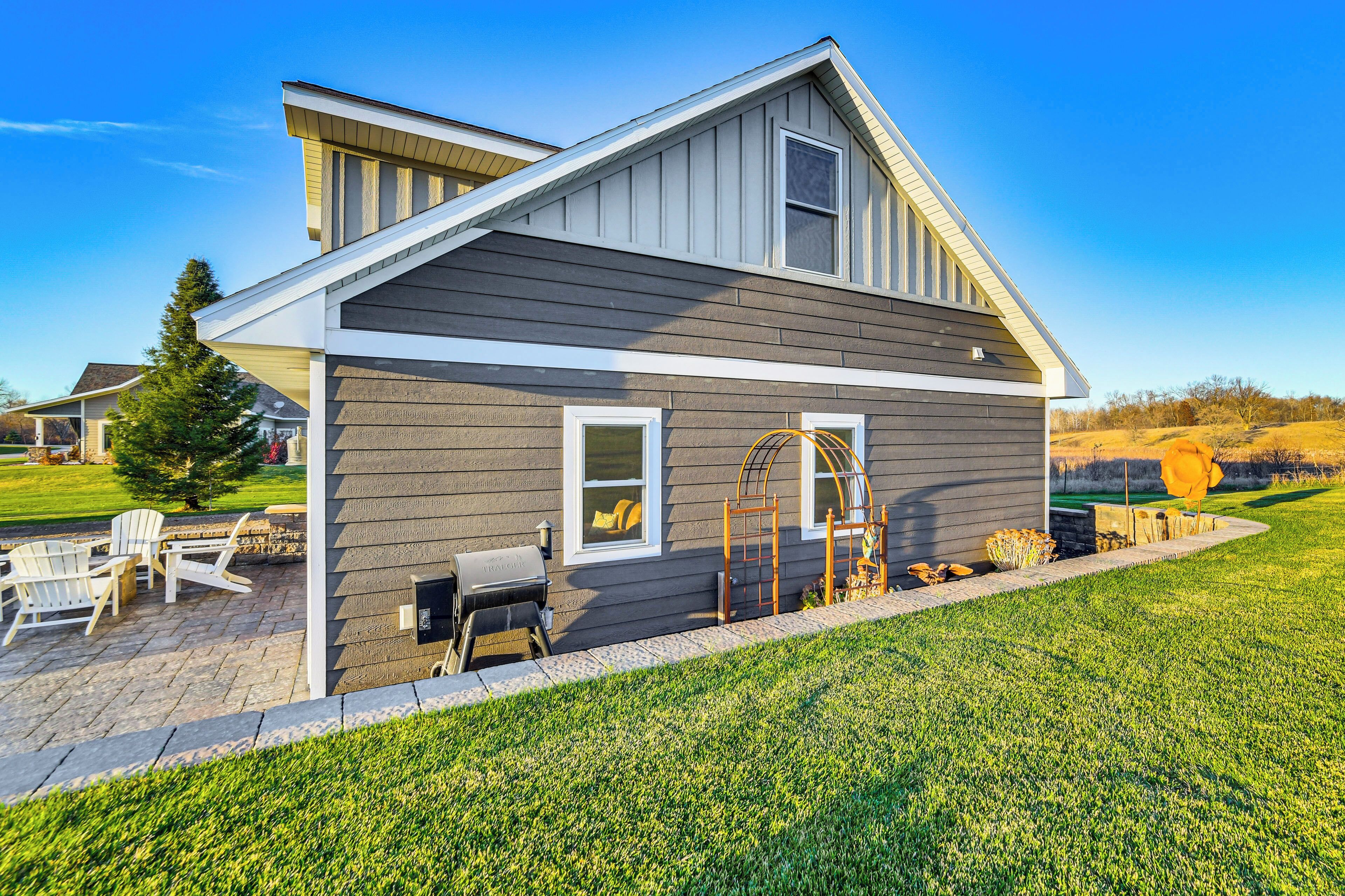 A modern house with a sloped roof, a covered patio with outdoor furniture, and a well-maintained lawn.