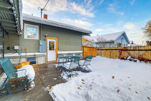 A house with a covered patio, a wooden fence, and a snow-covered yard. - 1 Mi to Dtwn Casper: Homey Getaway w/ Yard! (Casper)