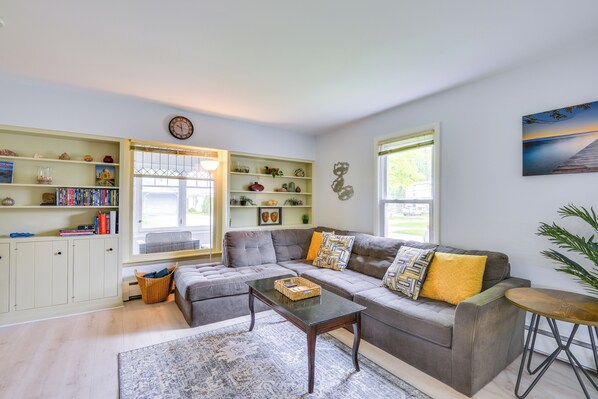 A modern living room with a sectional sofa, a coffee table, and a bookshelf.