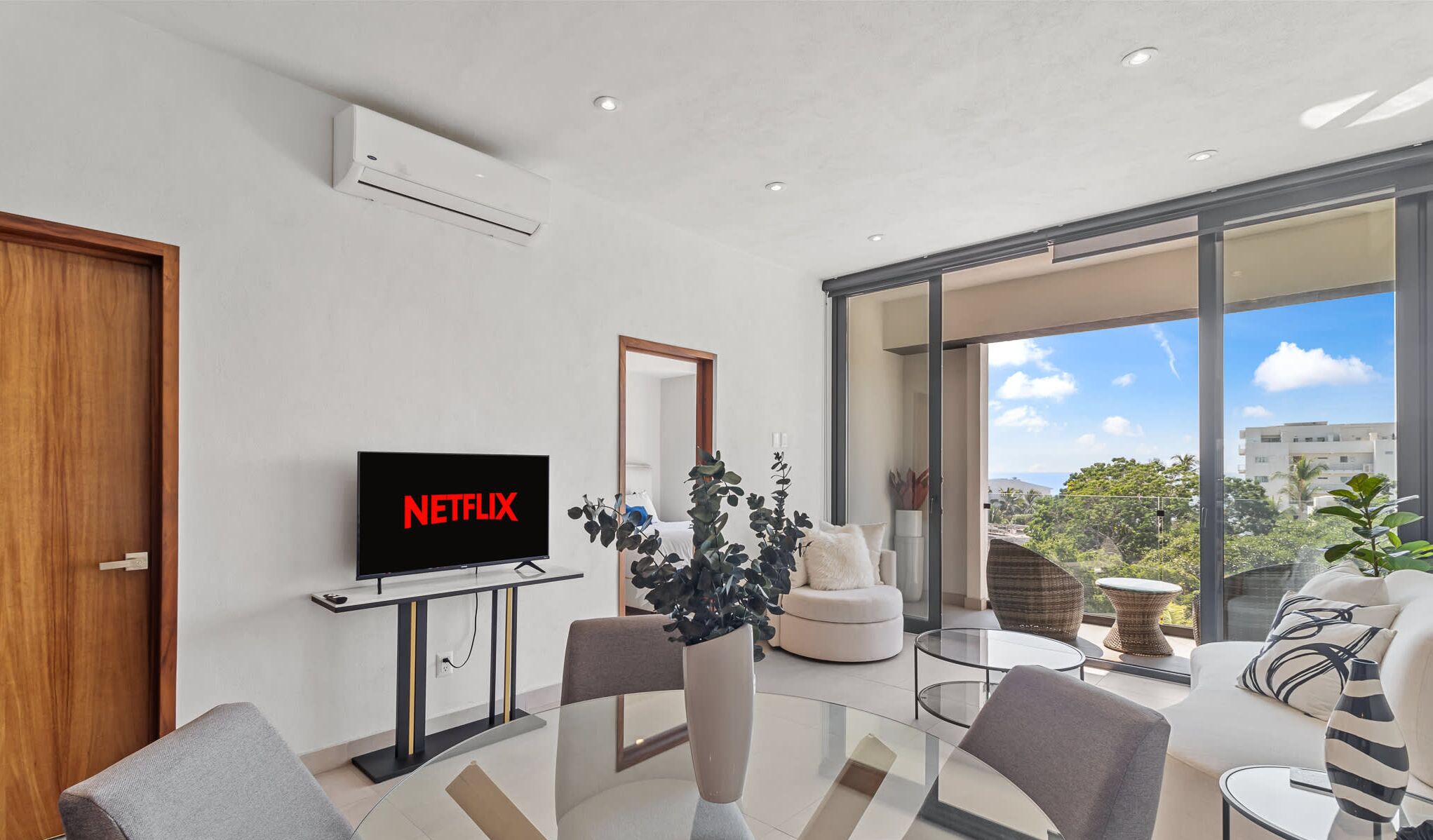 Moderni olohuone, jossa on litteänäyttöinen televisio, jonka ruudulla näkyy Netflixin logo, lasinen sohvapöytä ja sohva.
