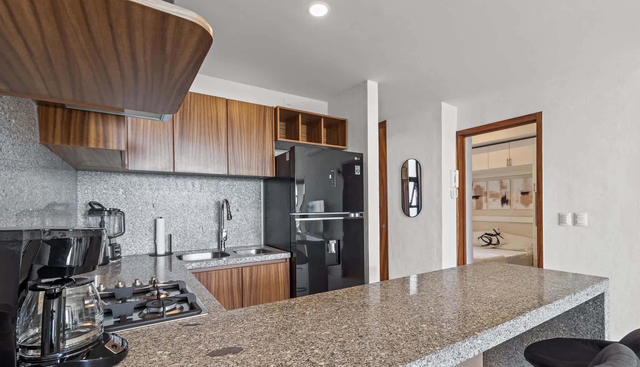 A modern kitchen with granite countertops, stainless steel appliances, and wooden cabinetry.