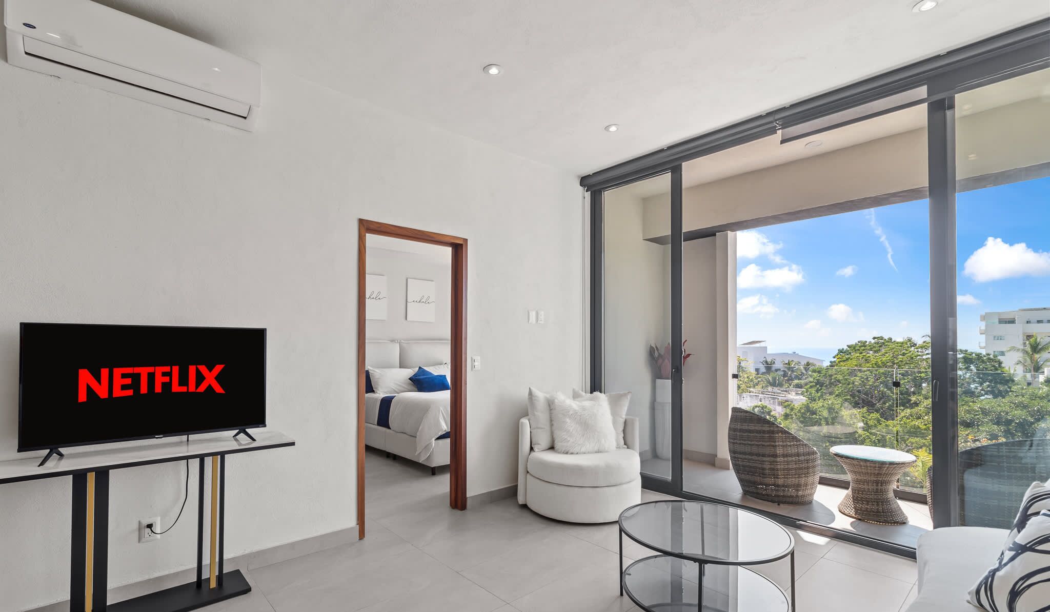 Un soggiorno moderno con TV a schermo piatto, un tavolino in vetro e vista sull'esterno.