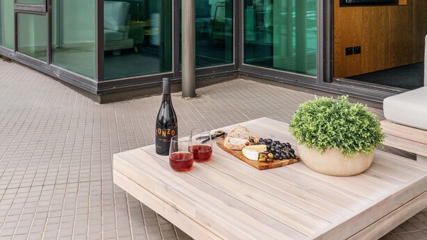 A modern outdoor seating area with a wooden table, a bottle of wine, and a small potted plant. - LUXURY LIVING - ICONIC ST KILDA BEACH LOCATION ** ONE MONTH SHORT STAYS **
 (St Kilda)
