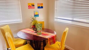 A dining area with a round table, yellow chairs, a fruit bowl, and a placemat. - Westside Magic 3bed 2 bath house in terrific westside of oahu!  (Nanakuli)