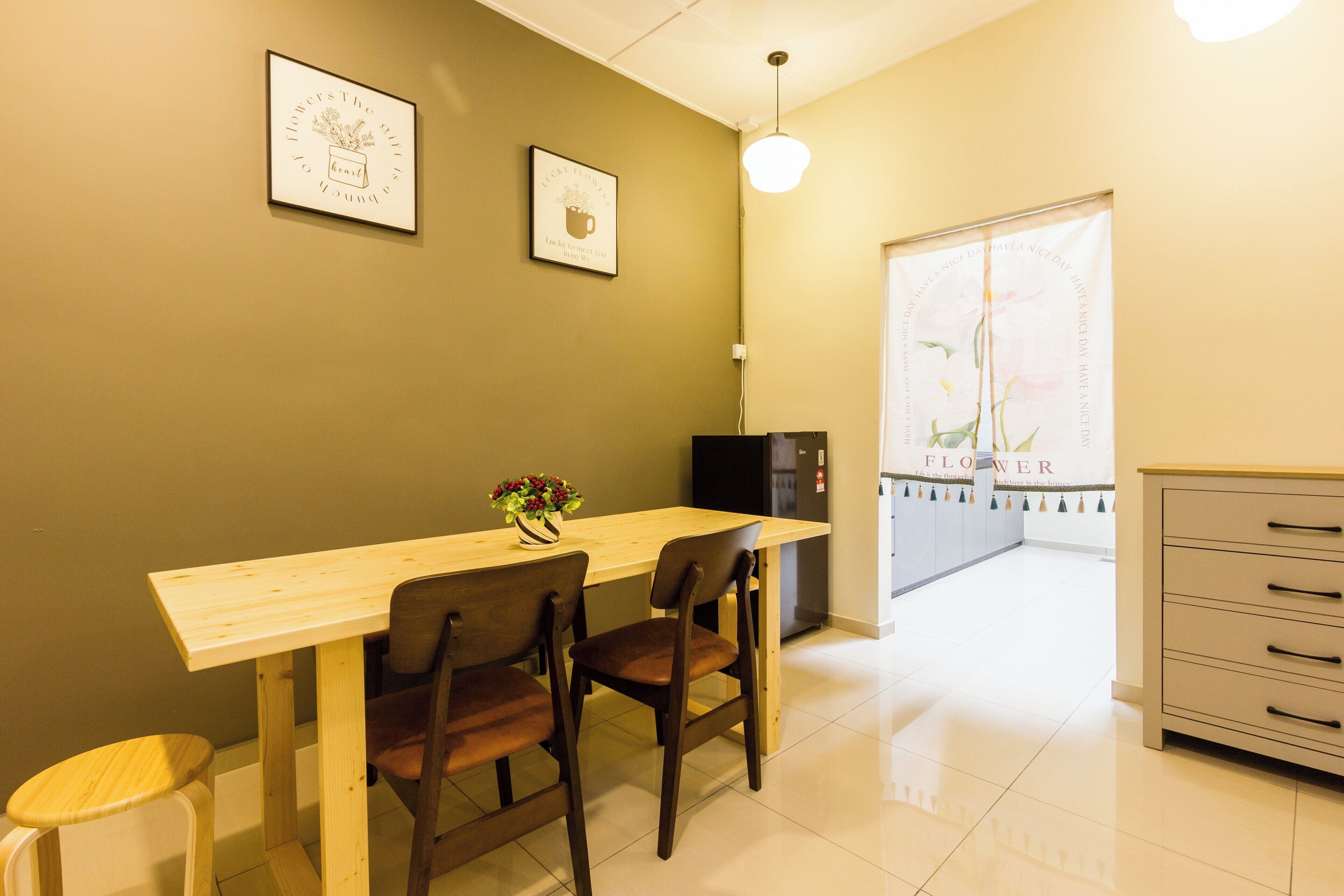 A small dining area with a wooden table and two chairs, a refrigerator, and a cabinet.