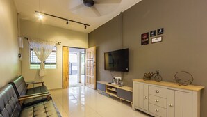 A modern living room with a sofa, TV, and a wooden cabinet. - Kimsar 3BR Family Inn by uBook (Perai)