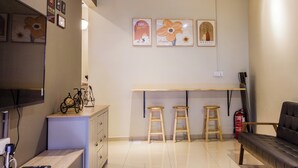 A living room with a sofa, a TV, a wooden bench, and a bar area with stools. - Kimsar 3BR Family Inn by uBook (Perai)