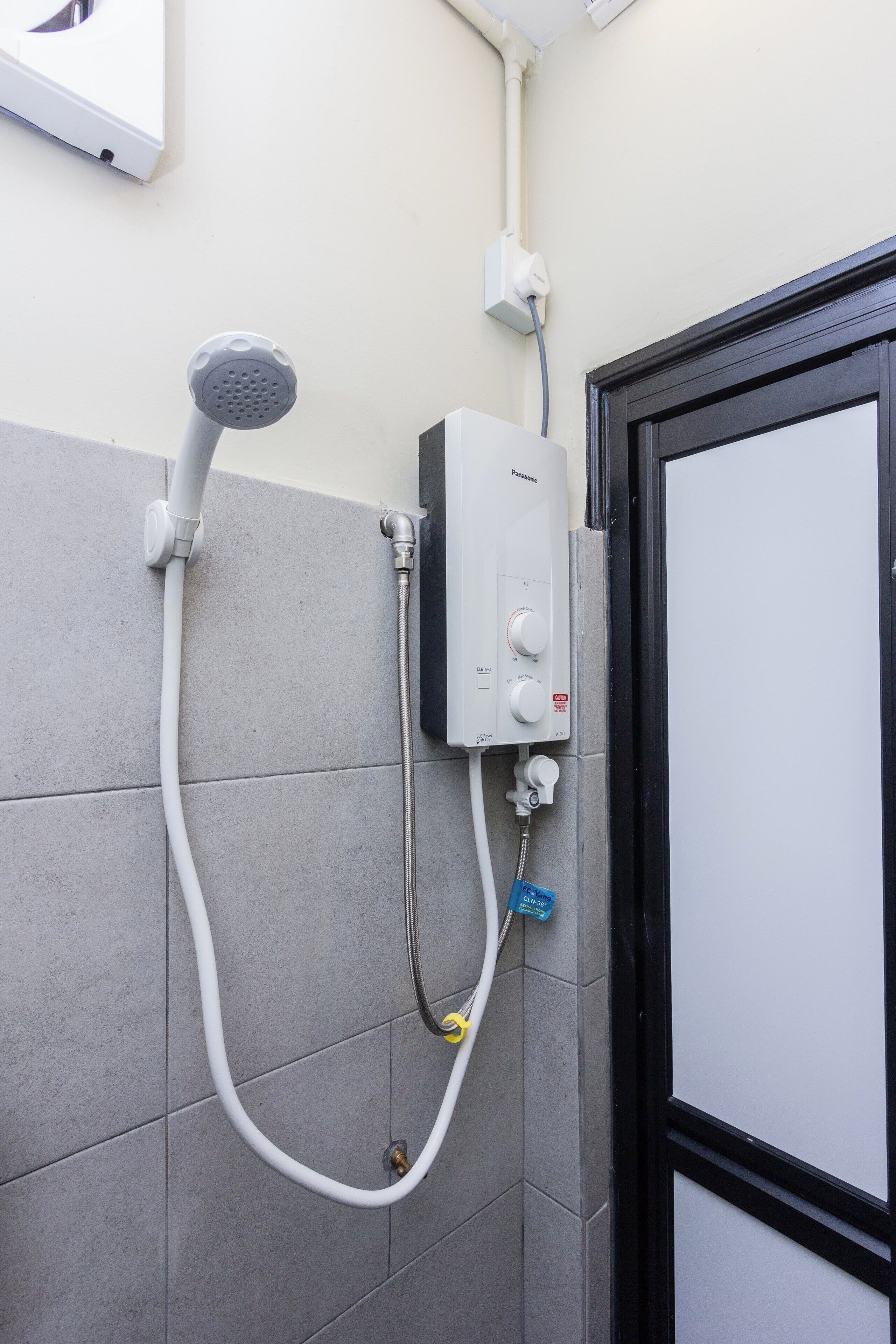 Un baño con ducha, panel de control y puerta.