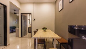 A dining area with a wooden table, chairs, and a vase of flowers. - Kimsar 3BR Family Inn by uBook (Perai)